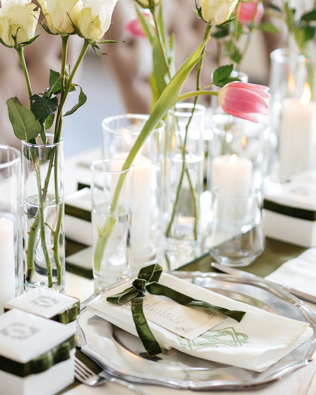 Stylish table setting for a wedding with white roses, pink tulips, and candles.