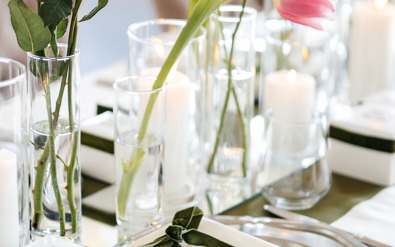 Stylish table setting for a wedding with white roses, pink tulips, and candles.