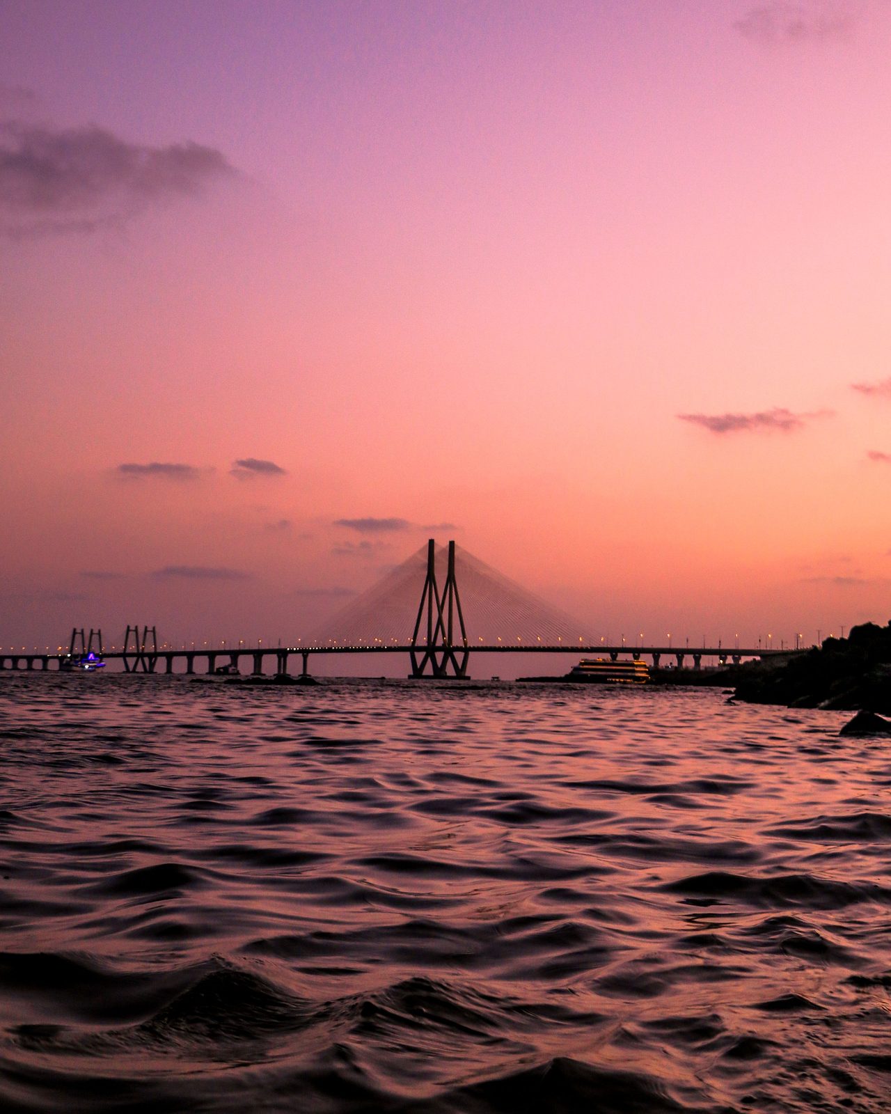 A serene view of the Bandra-Worli Sea Link at twilight with a vibrant pink sky over the Arabian Sea, Mumbai.