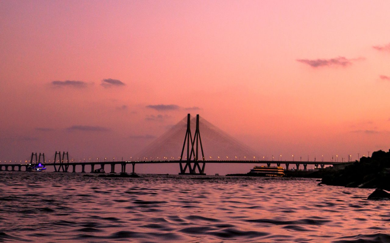 A serene view of the Bandra-Worli Sea Link at twilight with a vibrant pink sky over the Arabian Sea, Mumbai.