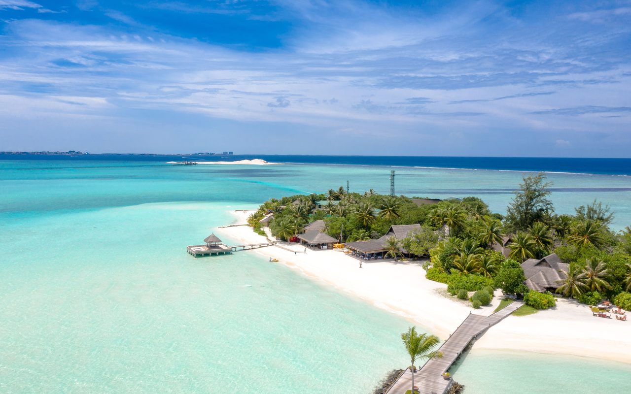 Aerial view of an idyllic tropical island resort with turquoise waters and sandy beaches.