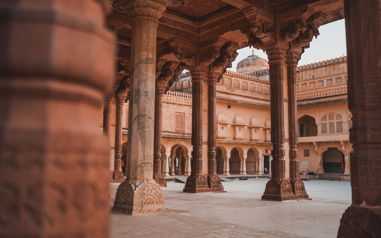 Beautiful pillars and arches of Jaipur palace courtyard showcasing intricate Indian architecture.