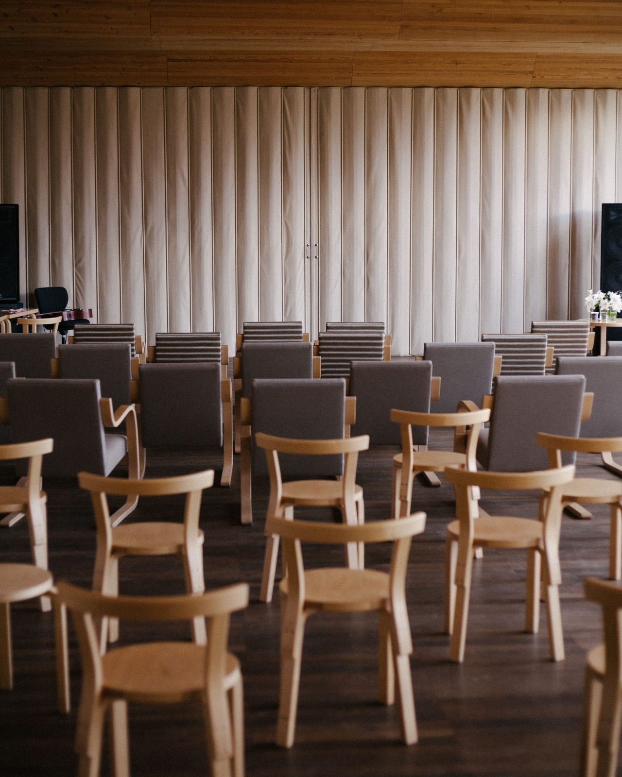 Empty modern auditorium with wooden chairs and stage setup, ideal for events.
