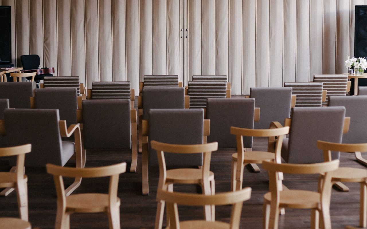 Empty modern auditorium with wooden chairs and stage setup, ideal for events.