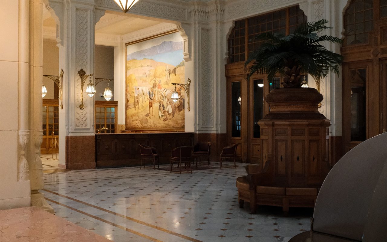 Elegant historic lobby with ornate architecture and warm lighting in an empty space.