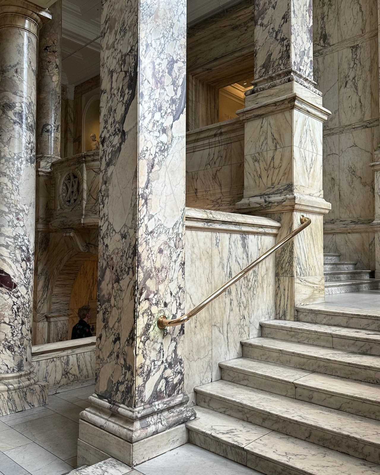A luxurious marble staircase in a historic interior setting with ornate columns.