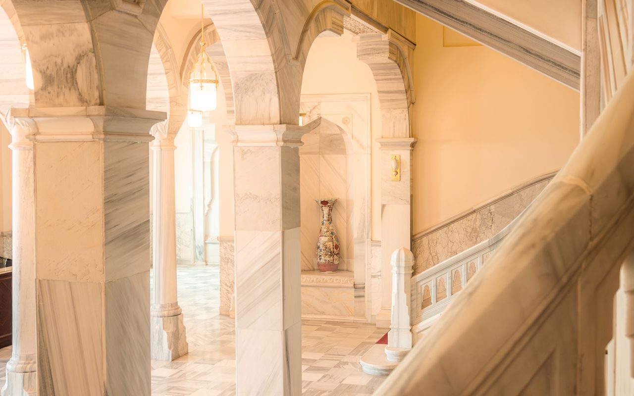 A luxurious marble staircase with arches in a sunlit interior, showcasing classic architecture.