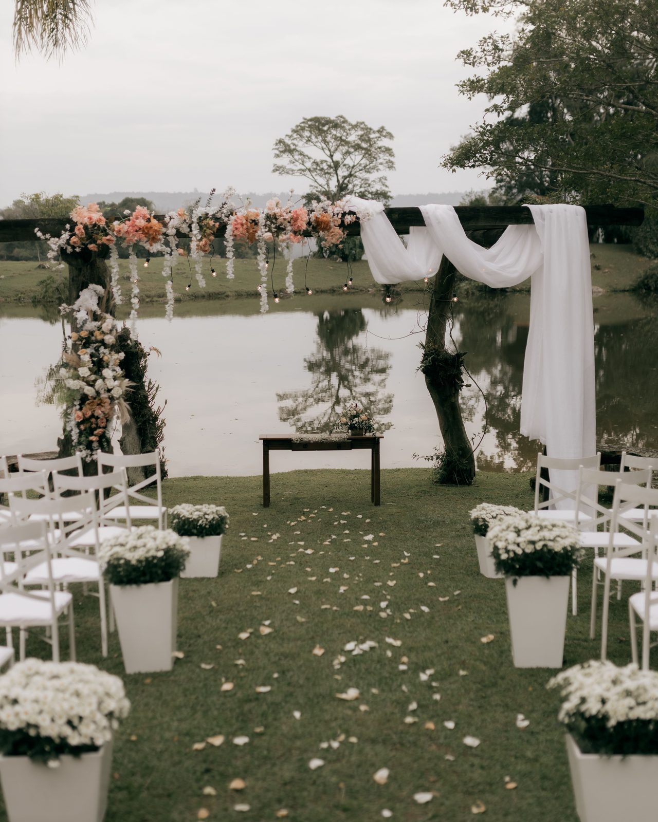 Beautiful floral wedding arch setup by a serene lakeside, ideal for outdoor ceremonies.