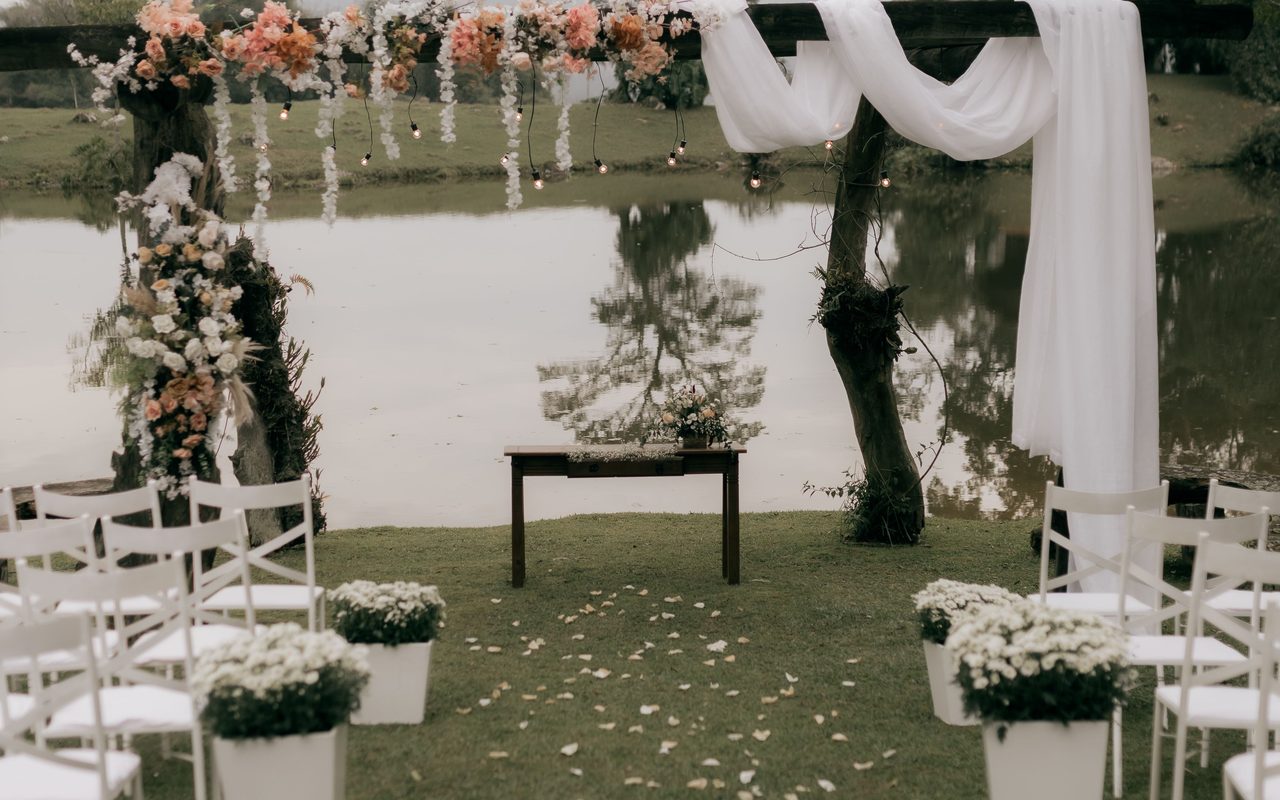 Beautiful floral wedding arch setup by a serene lakeside, ideal for outdoor ceremonies.