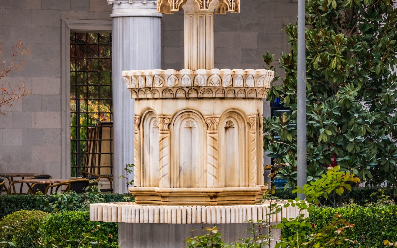Beautiful ornate stone fountain in a historical courtyard garden setting.
