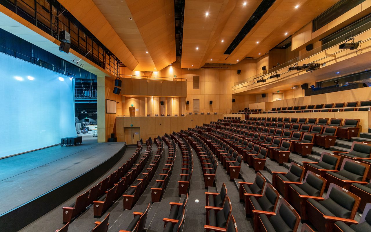 Spacious contemporary auditorium with empty seats and a stage, ideal for concerts or presentations.