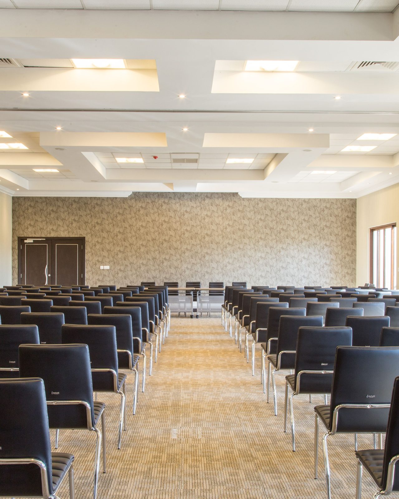 Spacious empty conference room with modern design and neatly arranged black chairs.