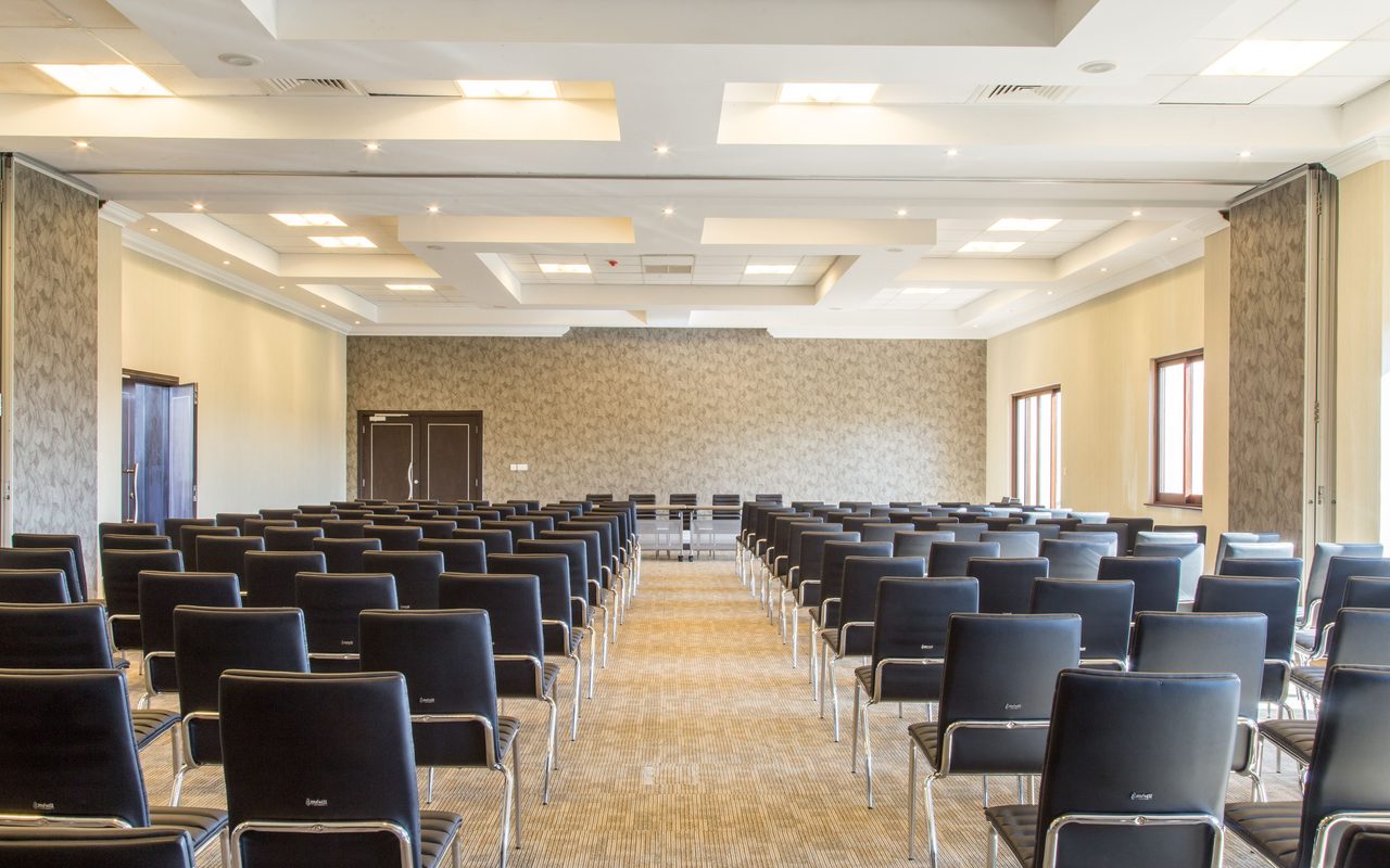 Spacious empty conference room with modern design and neatly arranged black chairs.