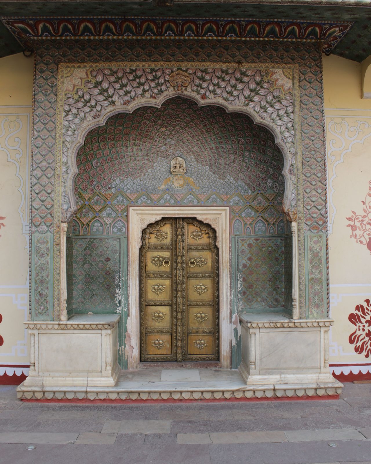 Beautifully ornate arched doorway at a historic Jaipur palace, showcasing intricate craftsmanship.