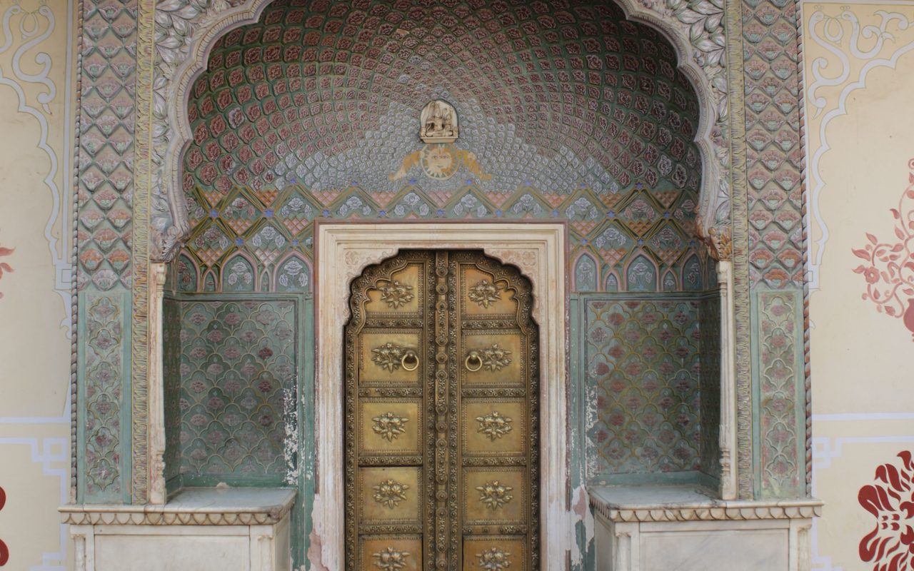 Beautifully ornate arched doorway at a historic Jaipur palace, showcasing intricate craftsmanship.