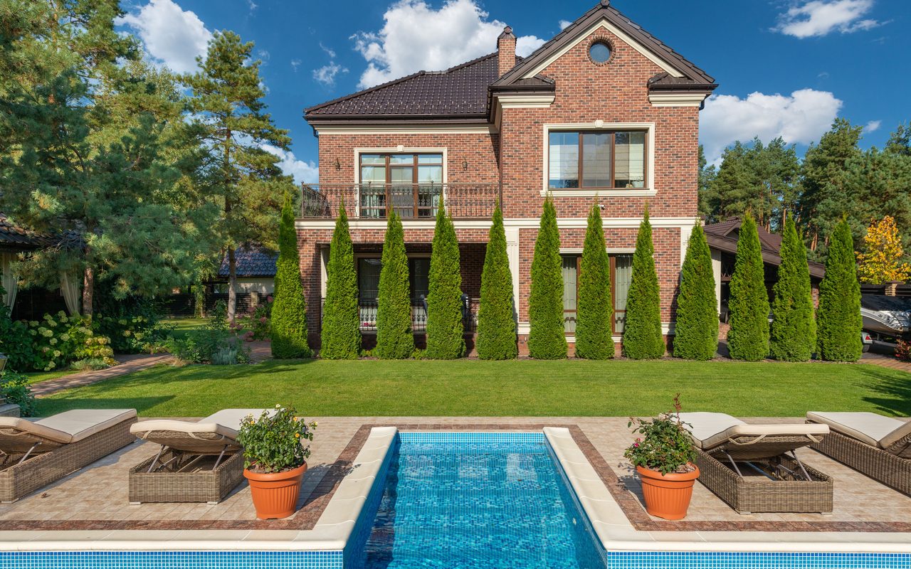 A stunning luxury villa with a refreshing pool and lush garden landscape, perfect for a relaxing outdoor retreat.