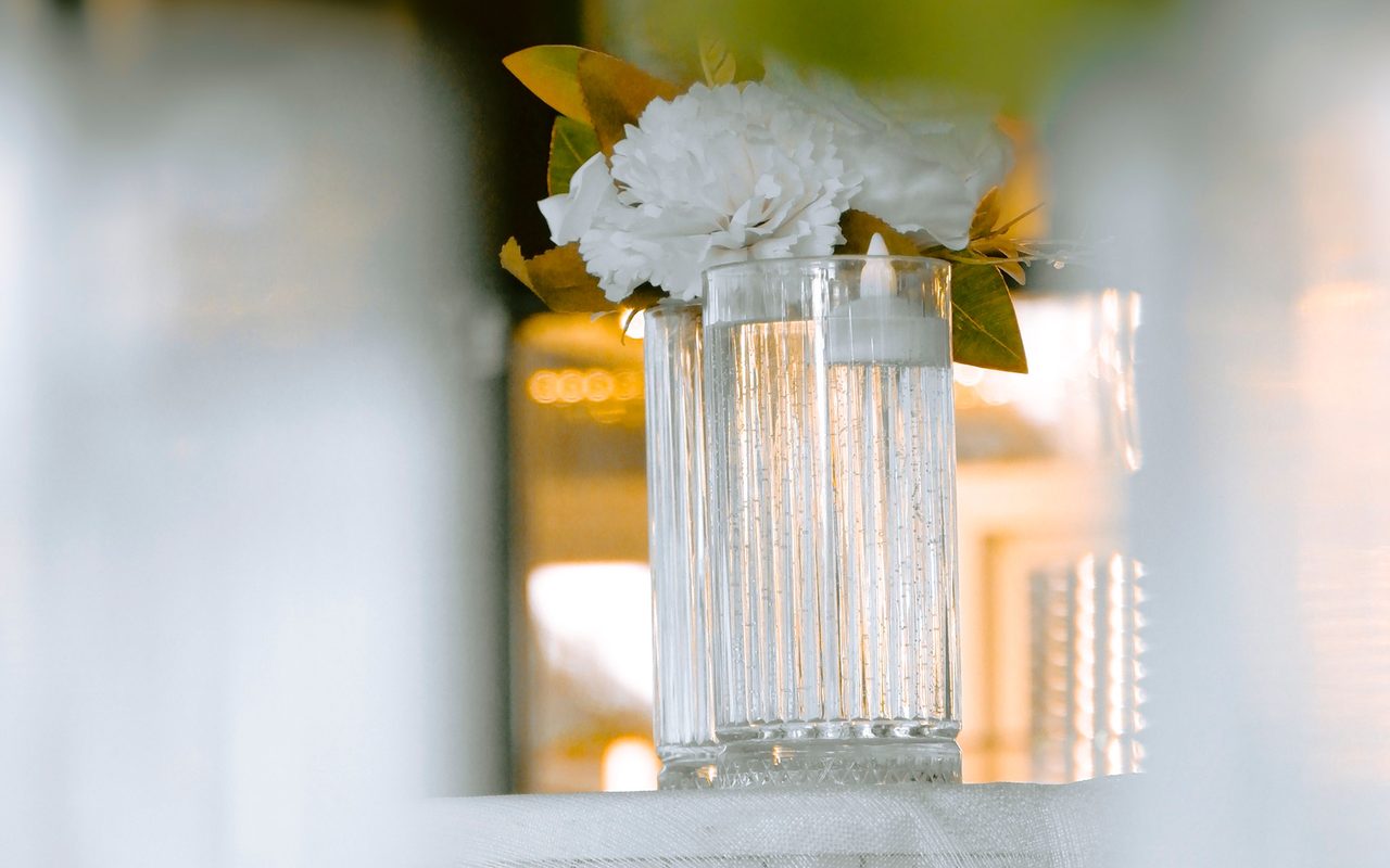White floral arrangement in a textured glass vase with soft background light