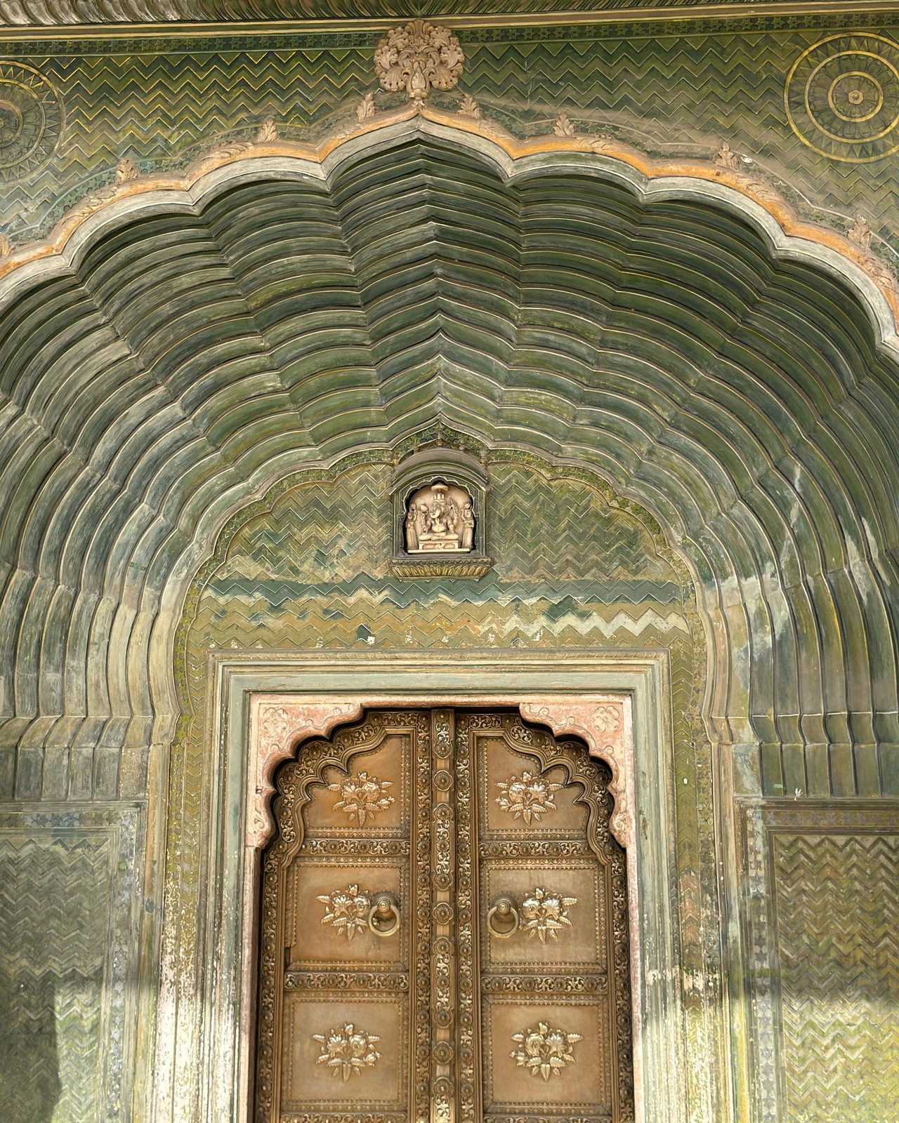 Detailed view of a beautifully ornate arch and carved door in Jaipur, India.