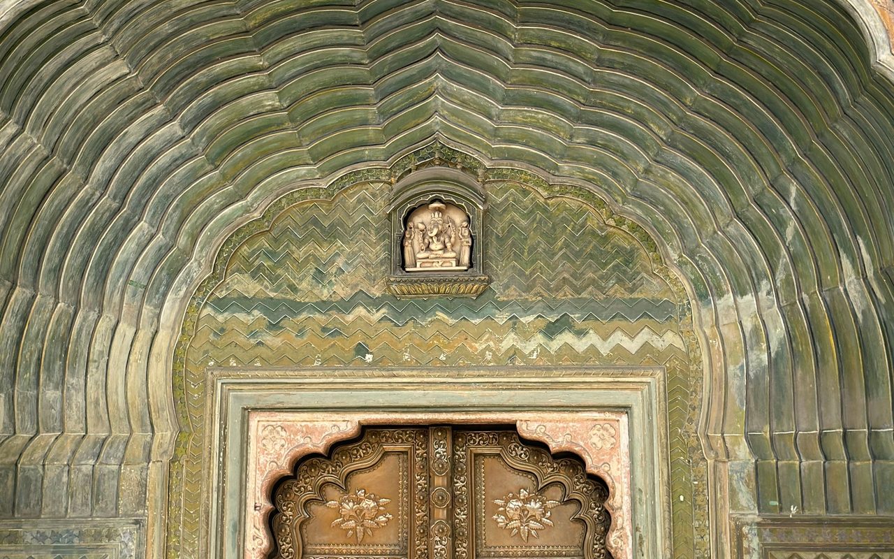 Detailed view of a beautifully ornate arch and carved door in Jaipur, India.
