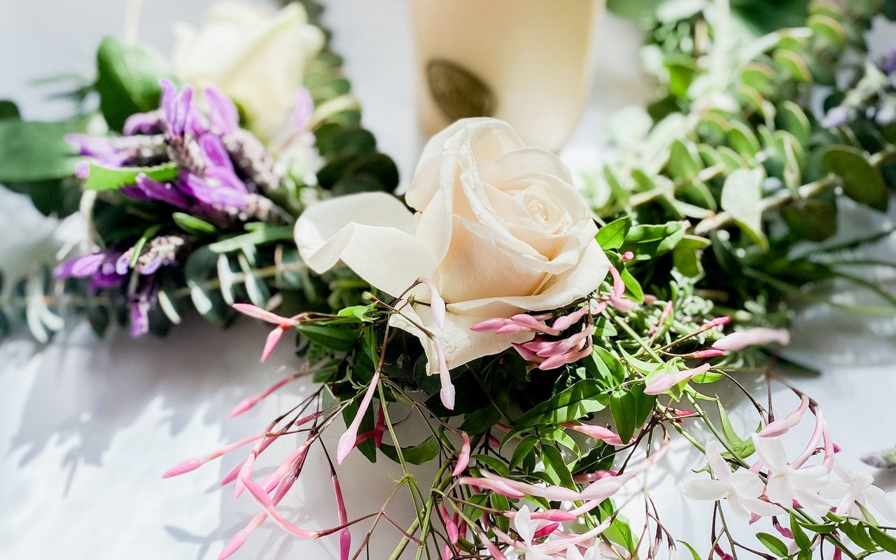 A beautiful arrangement of white roses and greenery with a lighted candle creates an elegant atmosphere.
