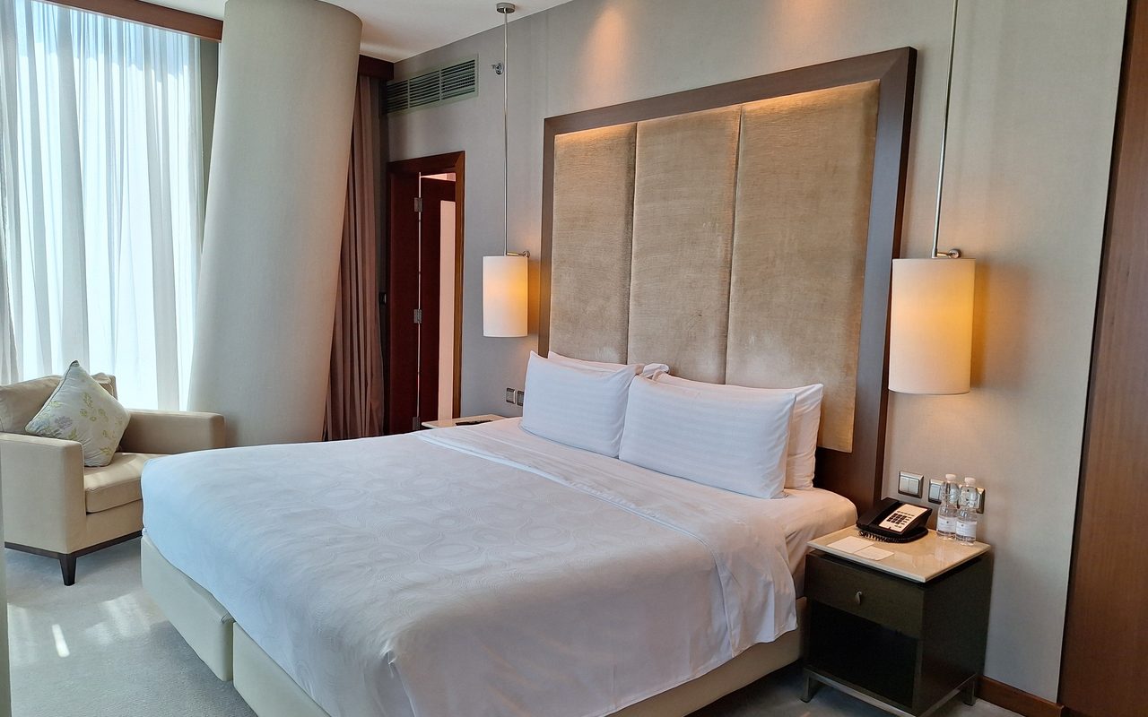 Elegant hotel bedroom with modern decor, twin lamps, and large window in Doha, Qatar.