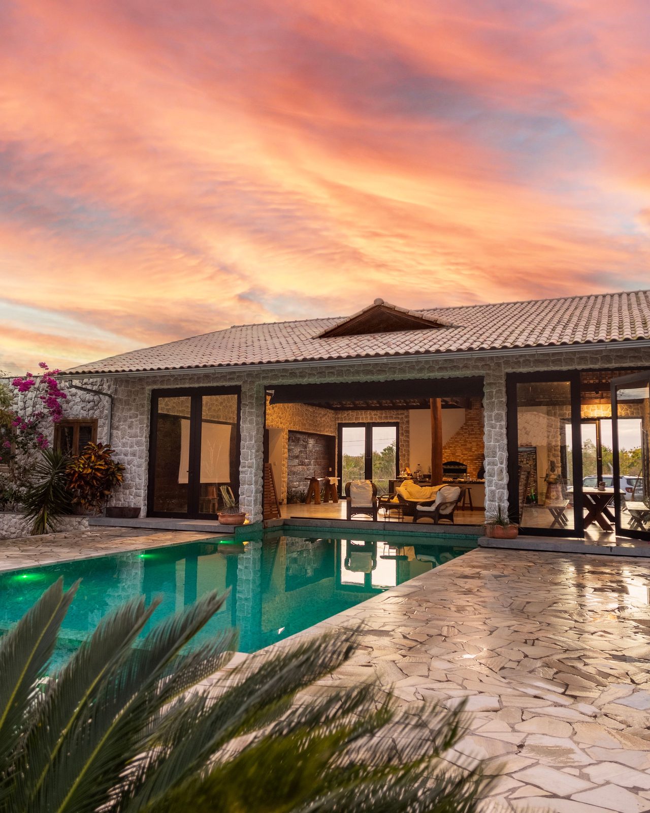 Beautiful stone villa with pool and vibrant sunset sky, perfect for luxury travel.