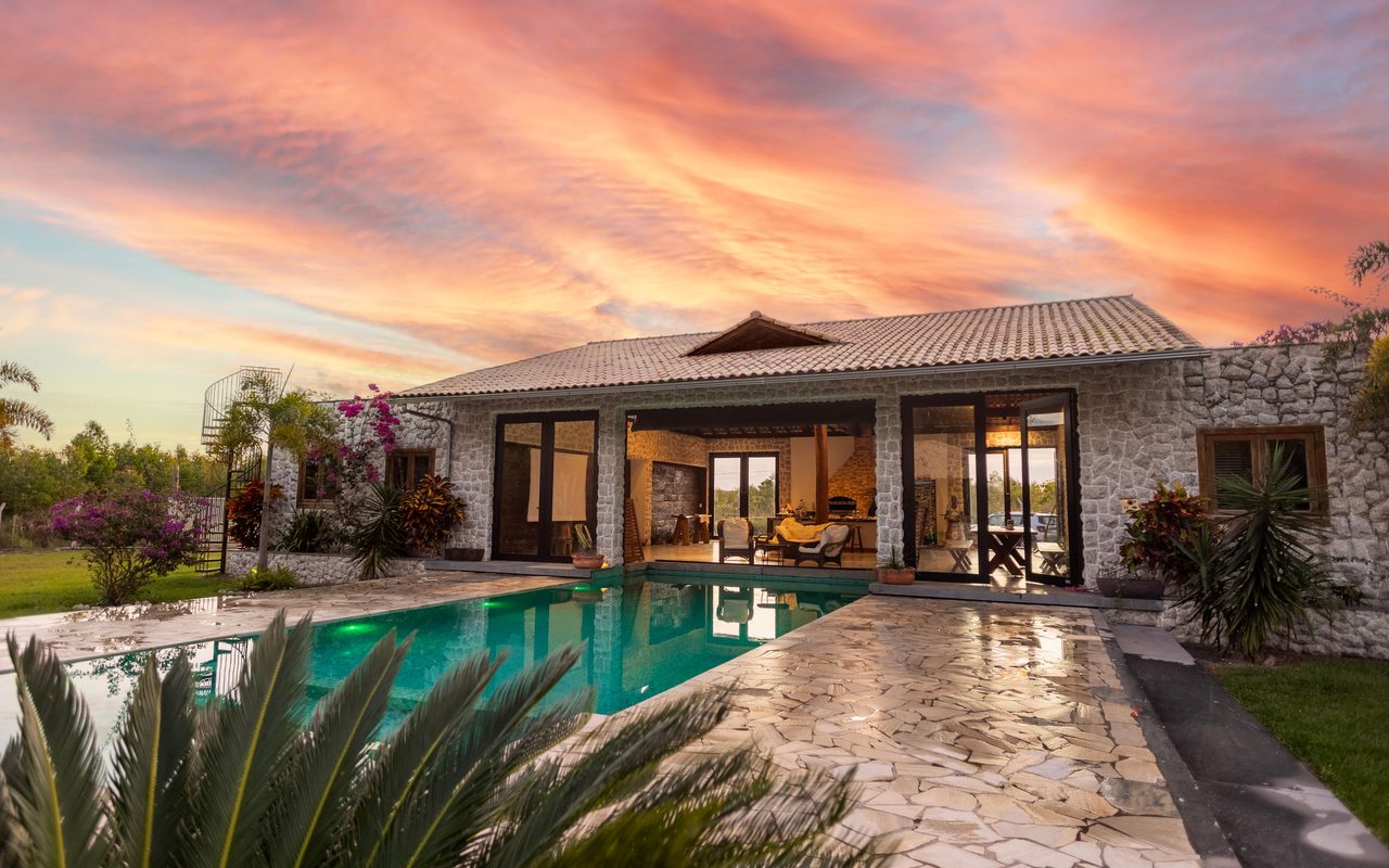 Beautiful stone villa with pool and vibrant sunset sky, perfect for luxury travel.