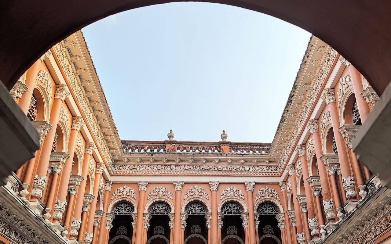 a historic pink palace courtyard with ornate arches and balconies.