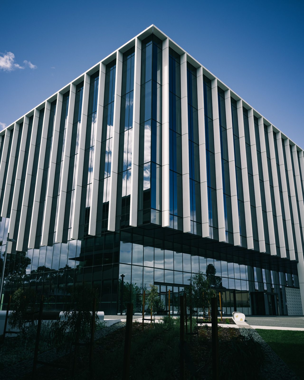 Architectural shot of a modern glass office building against a clear sky.