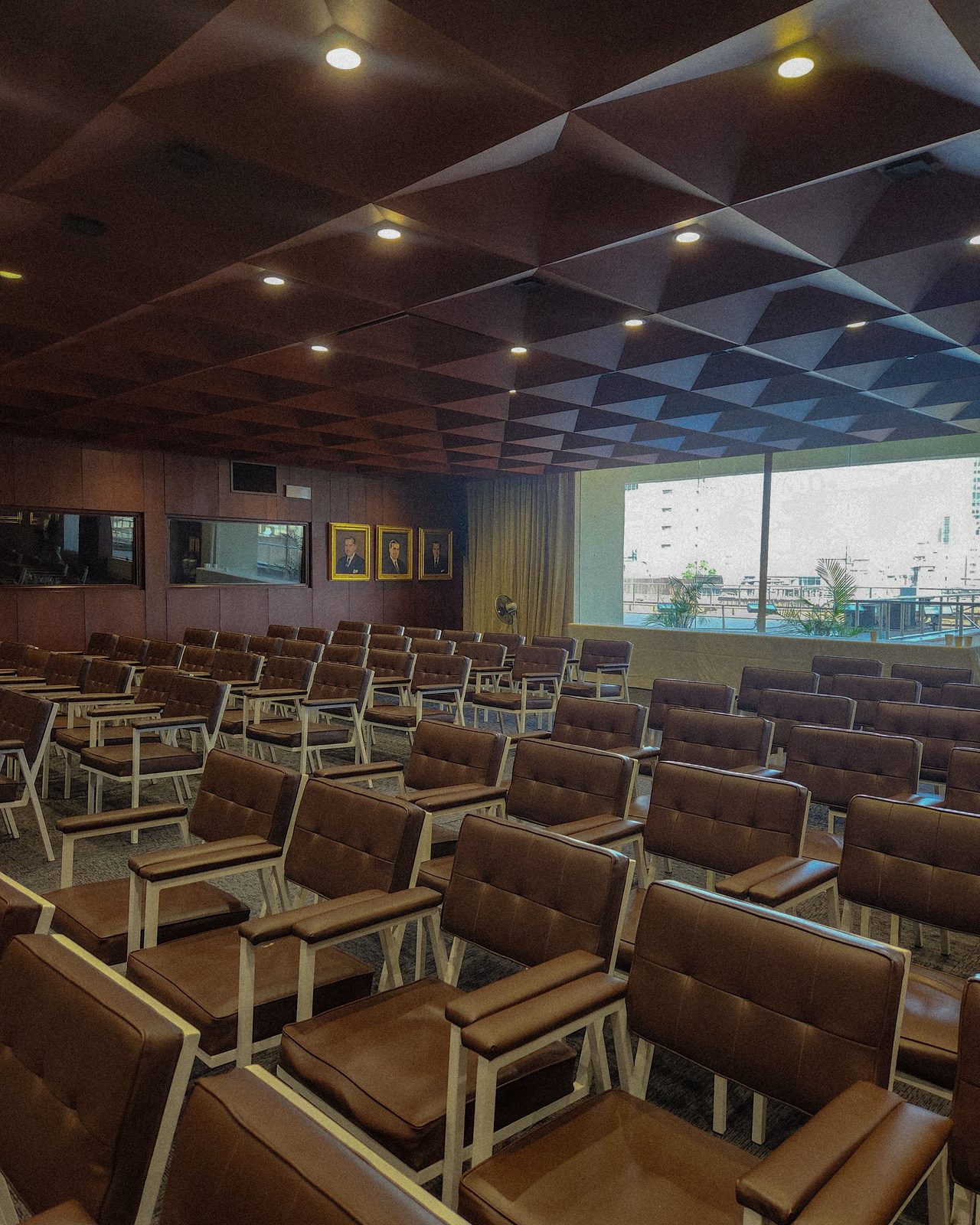 Empty modern conference room with brown cushioned seating and geometric ceiling design.