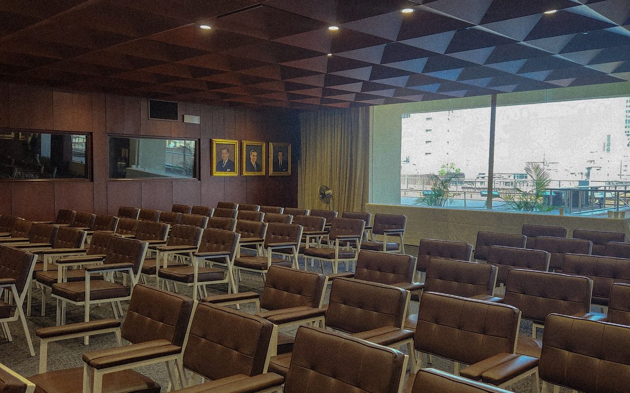 Empty modern conference room with brown cushioned seating and geometric ceiling design.