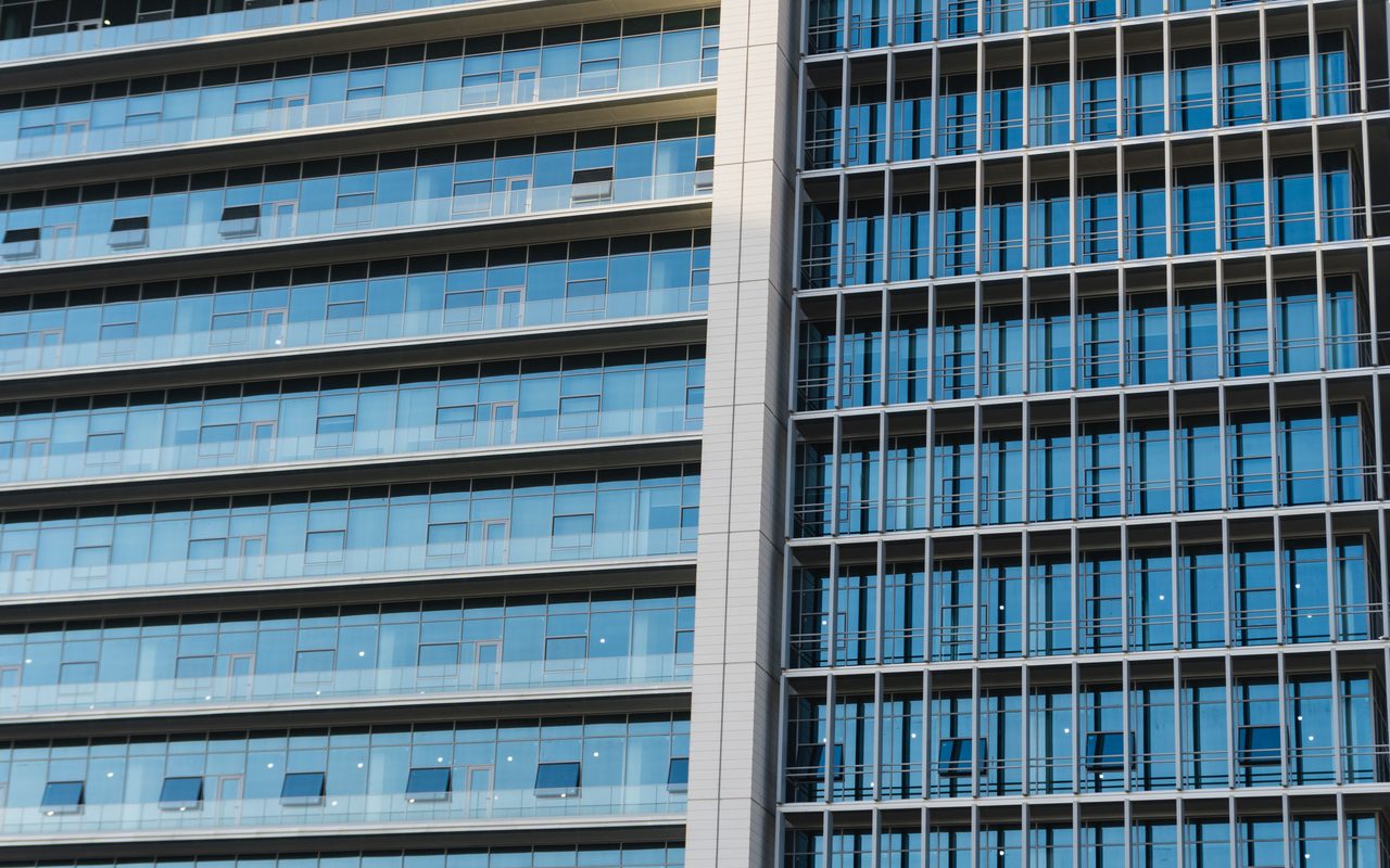 Detailed view of a modern highrise office building with glass windows and reflections.