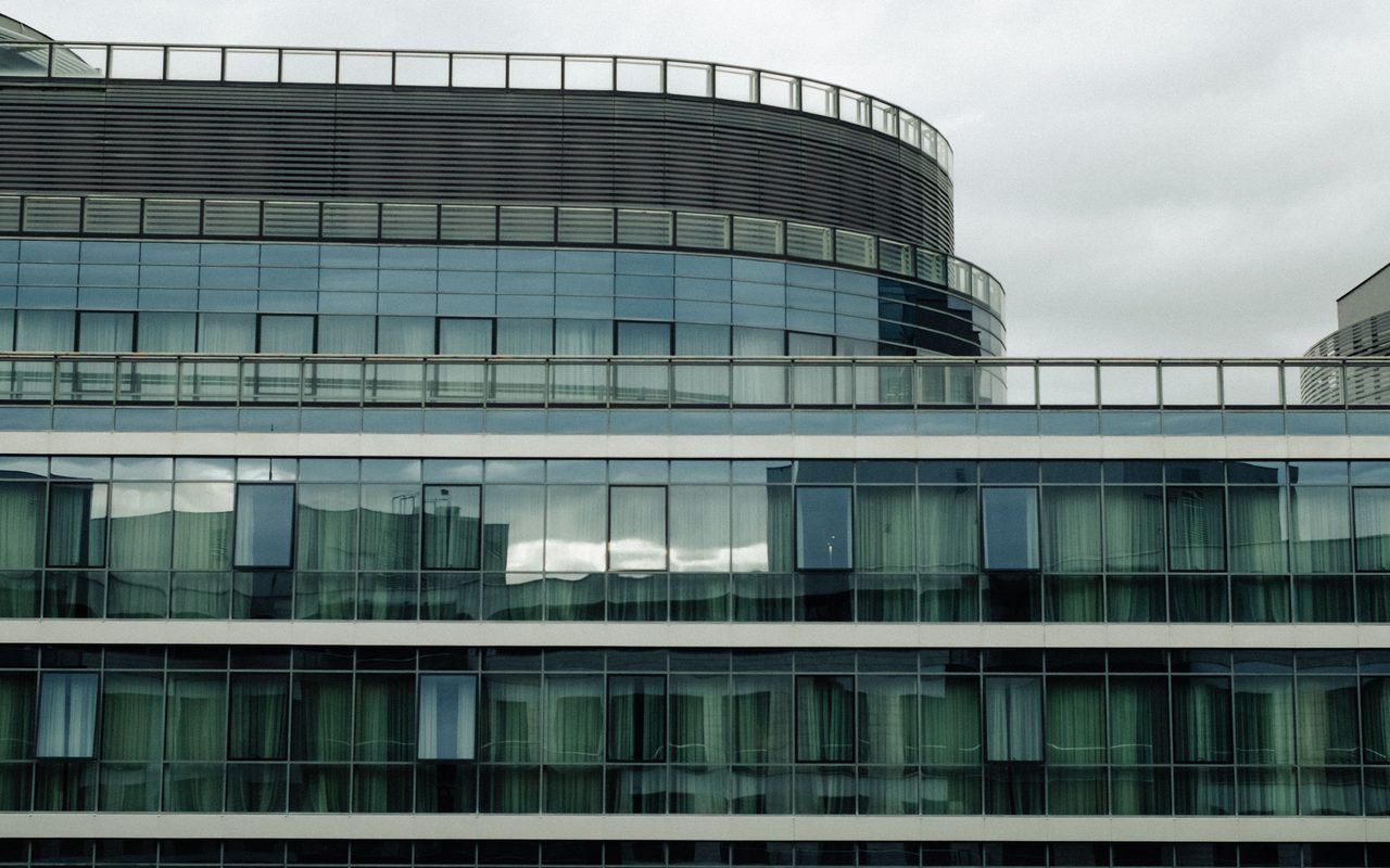 A modern office building with a sleek glass facade under an overcast sky.