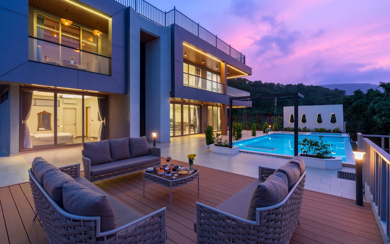 Stunning modern villa with outdoor seating and pool, captured at sunset.