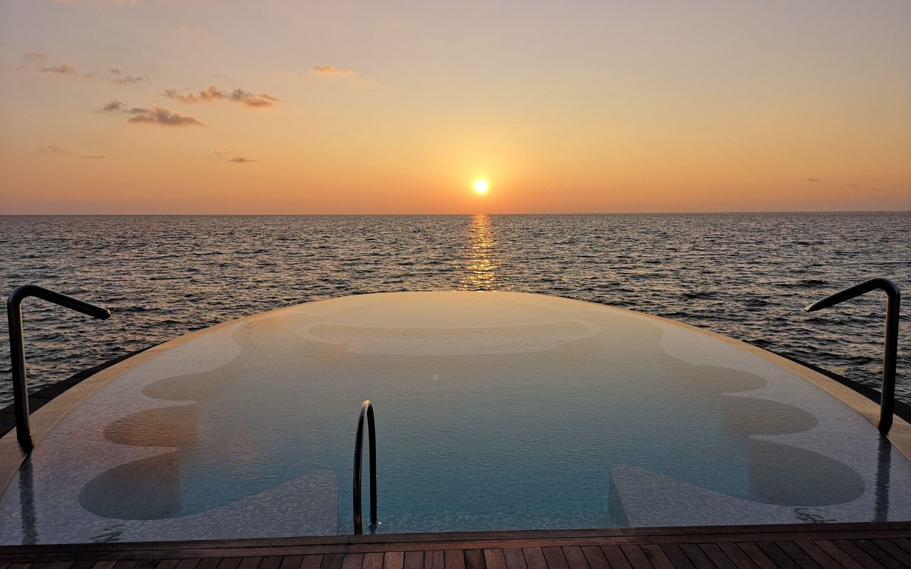 Infinity pool opening to an ocean horizon at sunset