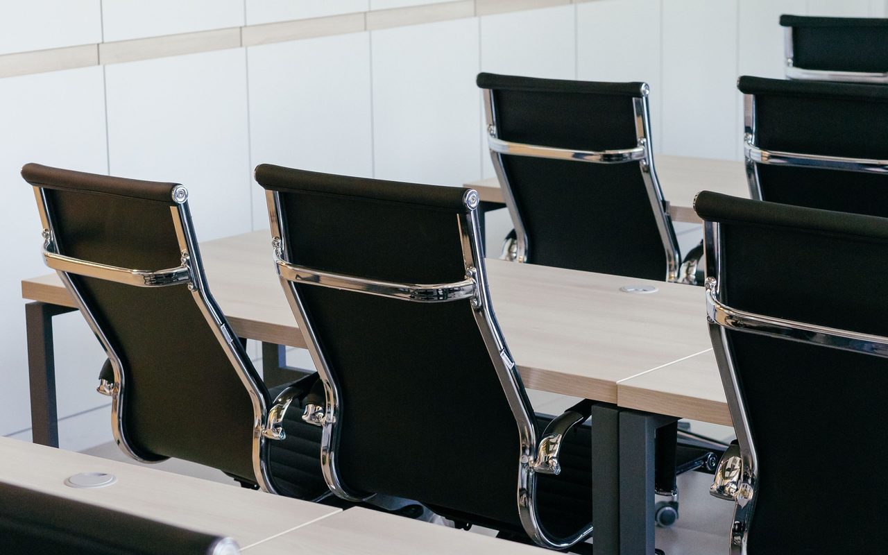 Empty modern conference room with sleek black chairs and wooden desks, perfect for business meetings.
