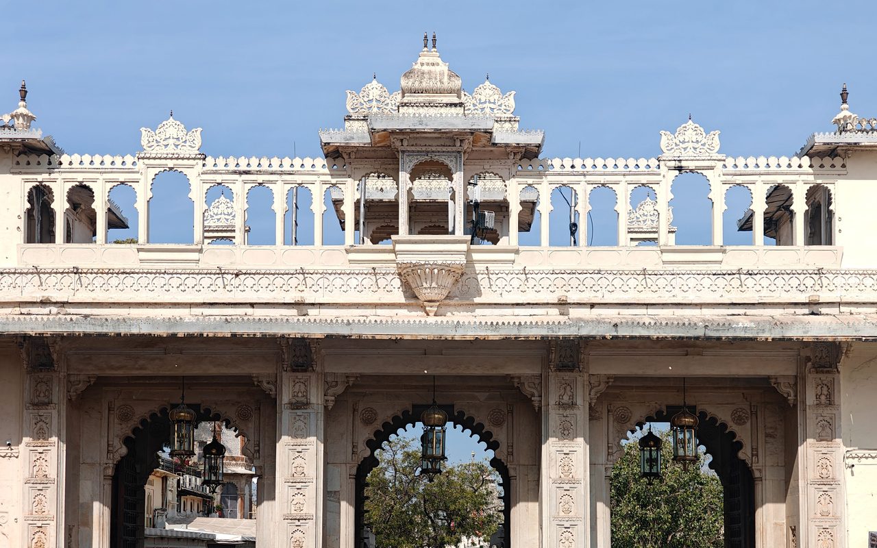 Crowds gather under the ornate gateway of Udaipur City Palace, a historic architectural gem.