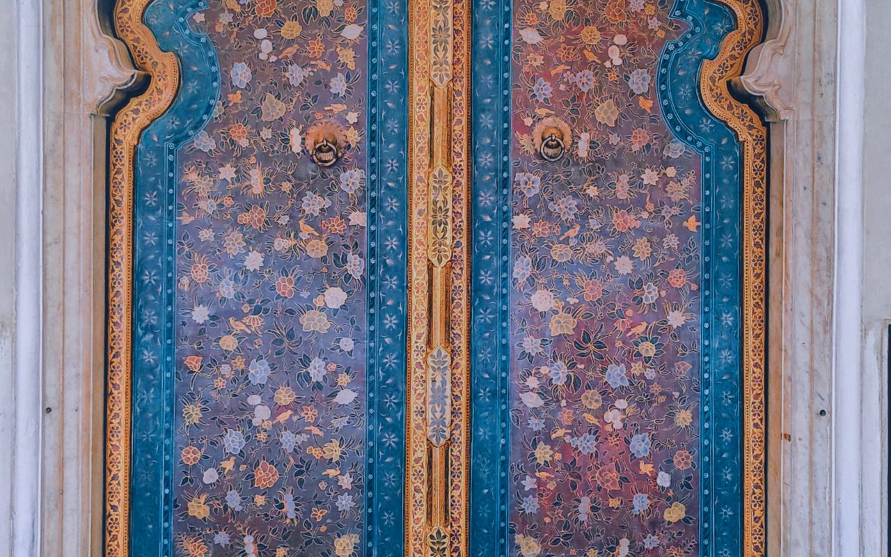 Intricately carved and painted wooden door with traditional Indian motifs in vibrant colors.