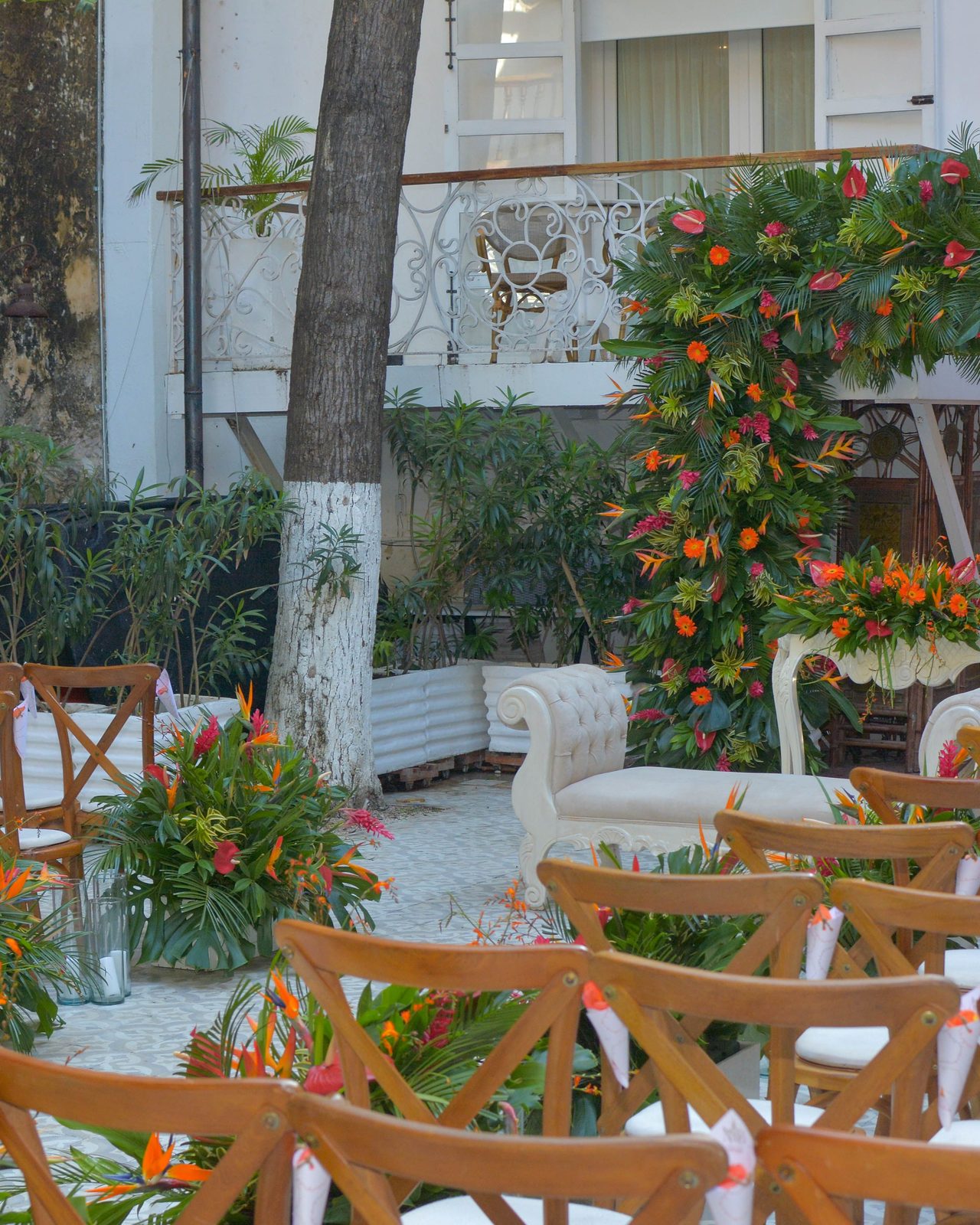 A beautifully decorated outdoor wedding ceremony with a floral arch and elegant seating arrangement.