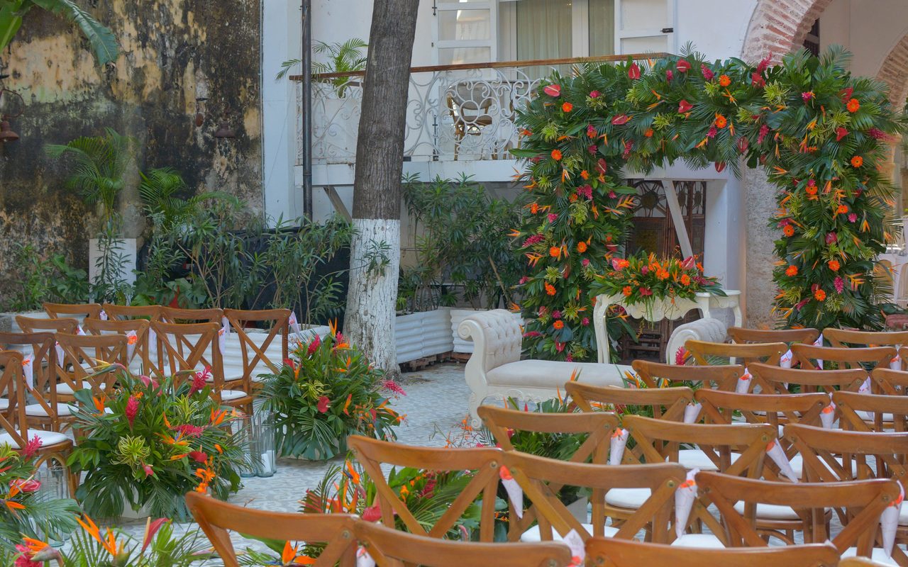A beautifully decorated outdoor wedding ceremony with a floral arch and elegant seating arrangement.
