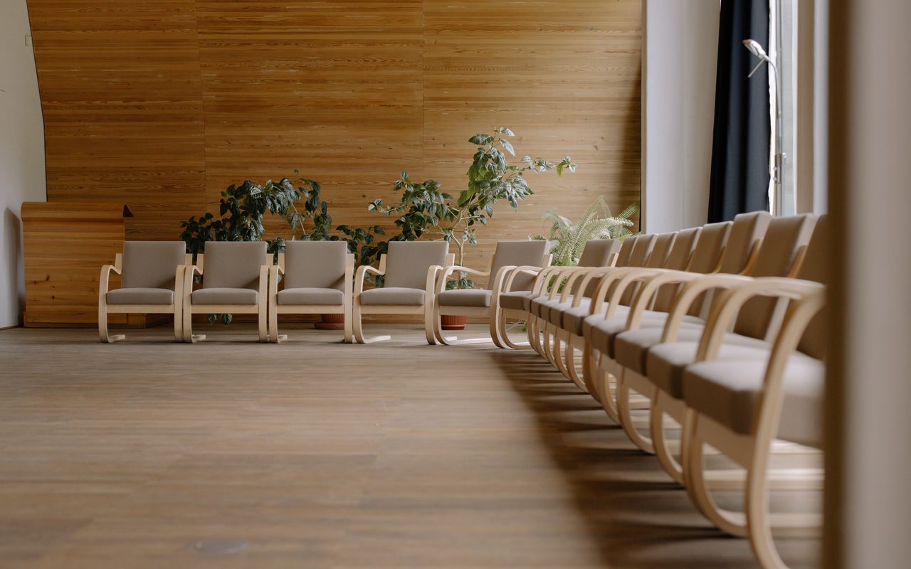 Spacious modern conference hall with wooden chairs and potted plants, perfect for events.