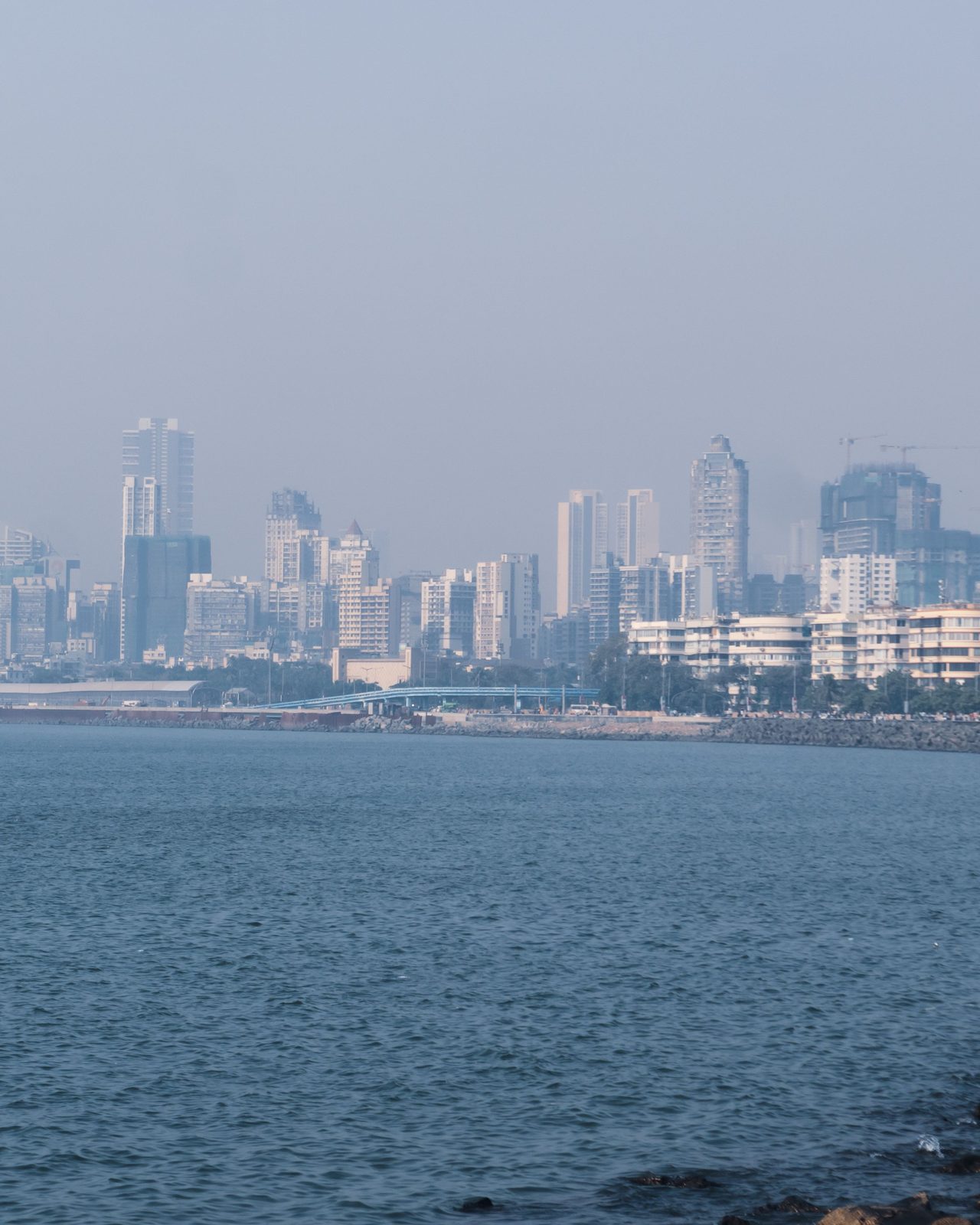 Marine Drive with Mumbai skyline and Arabian Sea under a clear sky.