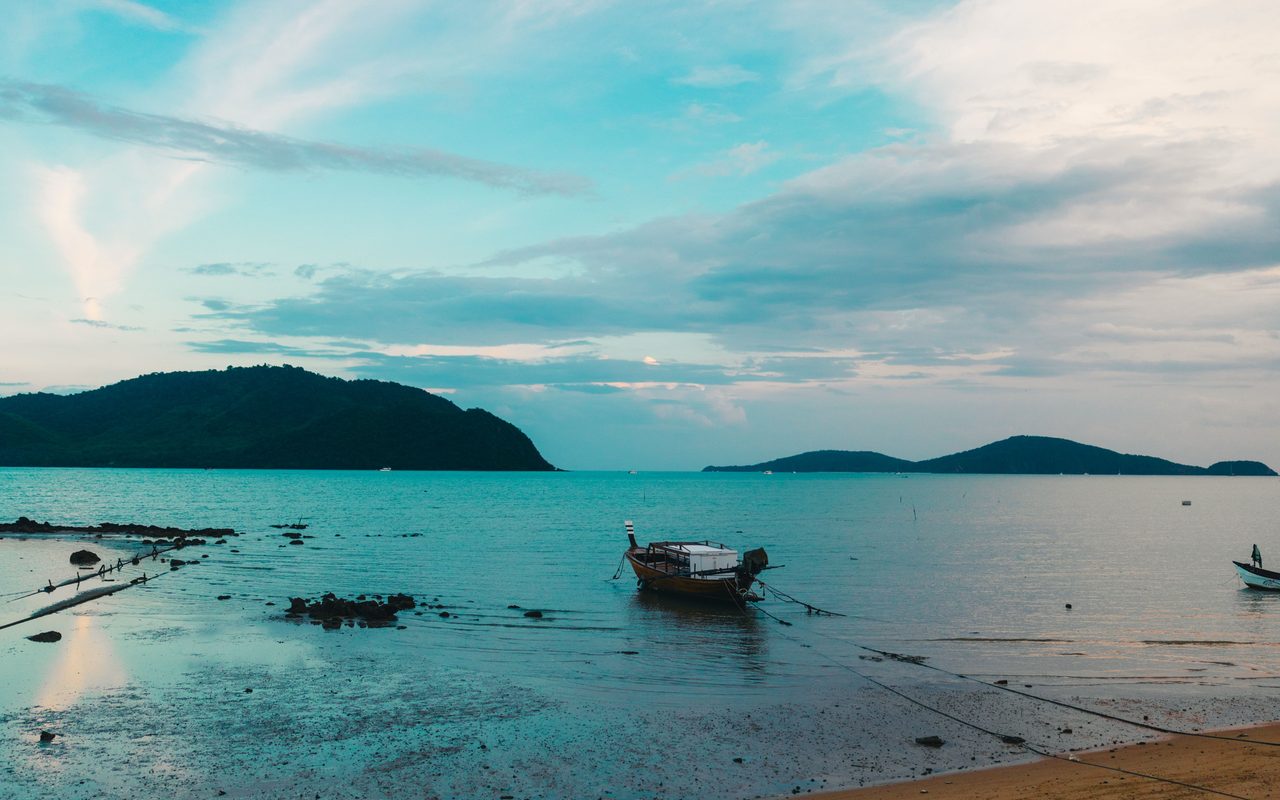 Tranquil beachfront view with boats and islands in Phuket, perfect for a serene escape.