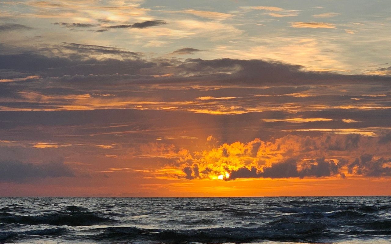 Beautiful sunset over a tranquil beach in Goa, India, showcasing colorful skies and gentle waves.