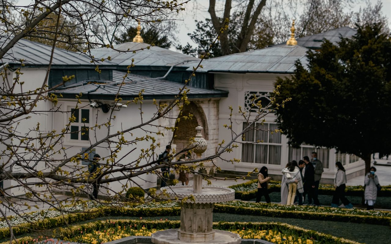 A serene garden with a central fountain surrounded by classic architecture and blooming flowers.