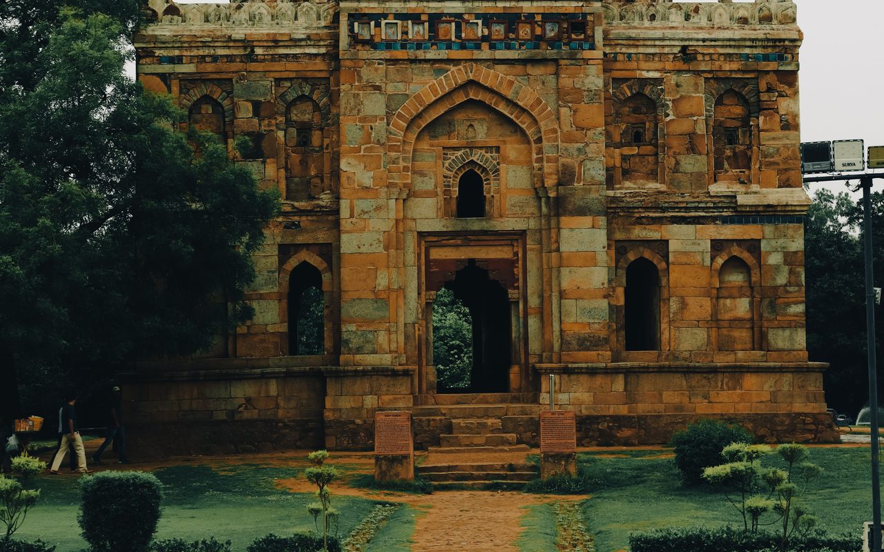 A historic tomb with a dome surrounded by lush gardens in New Delhi, India.