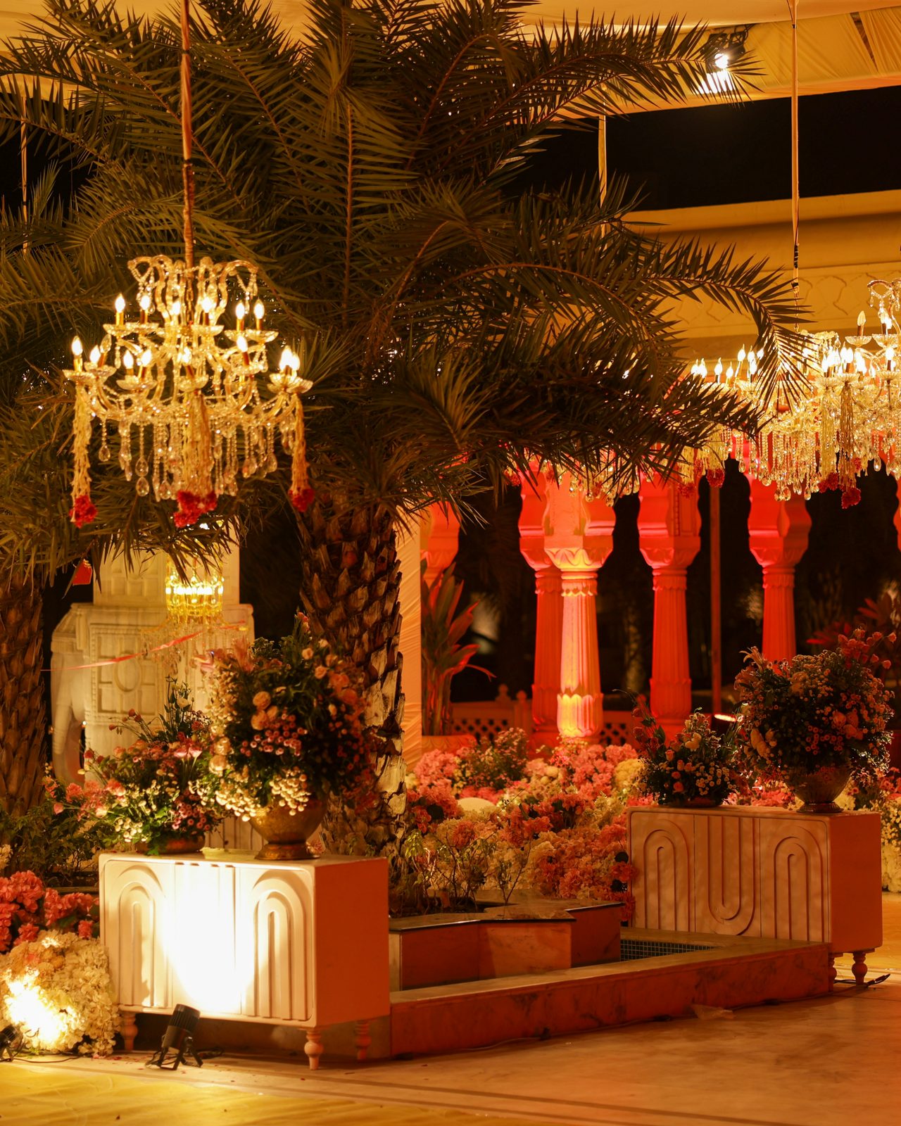 Floral wedding installation with crystal chandeliers in warm evening light