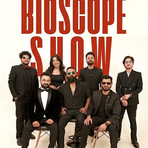 The band performing live on stage with singers, guitar, drums and keyboards at The Bioscope Show.