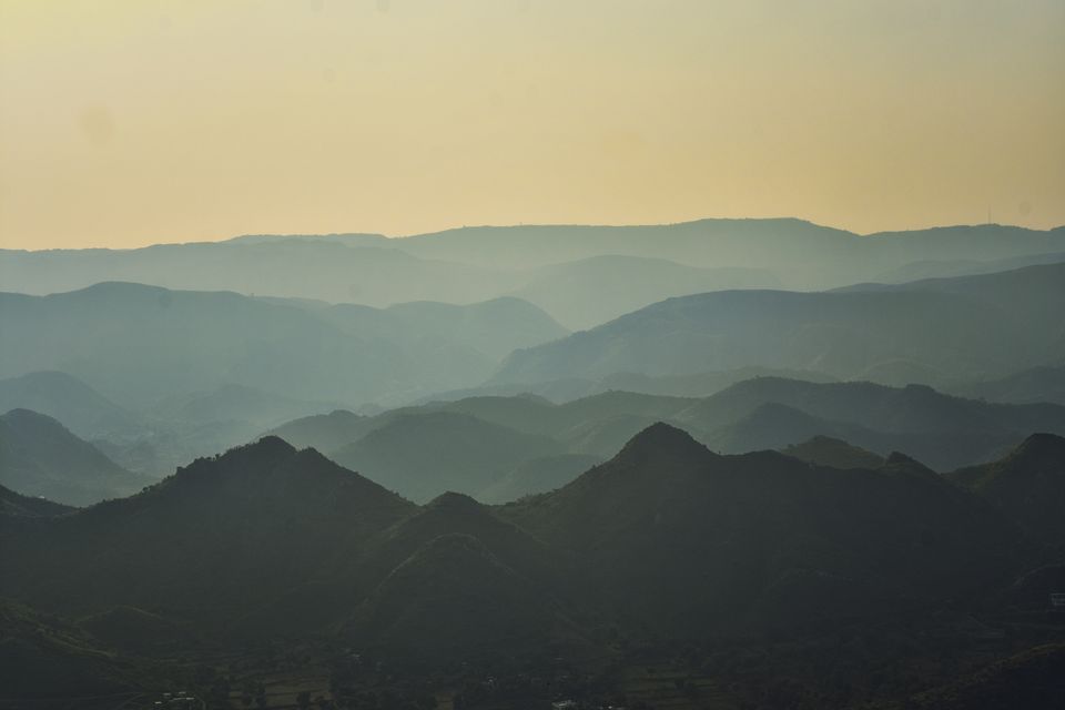 Layers of hills in the Aravalli Range beneath a golden sky
