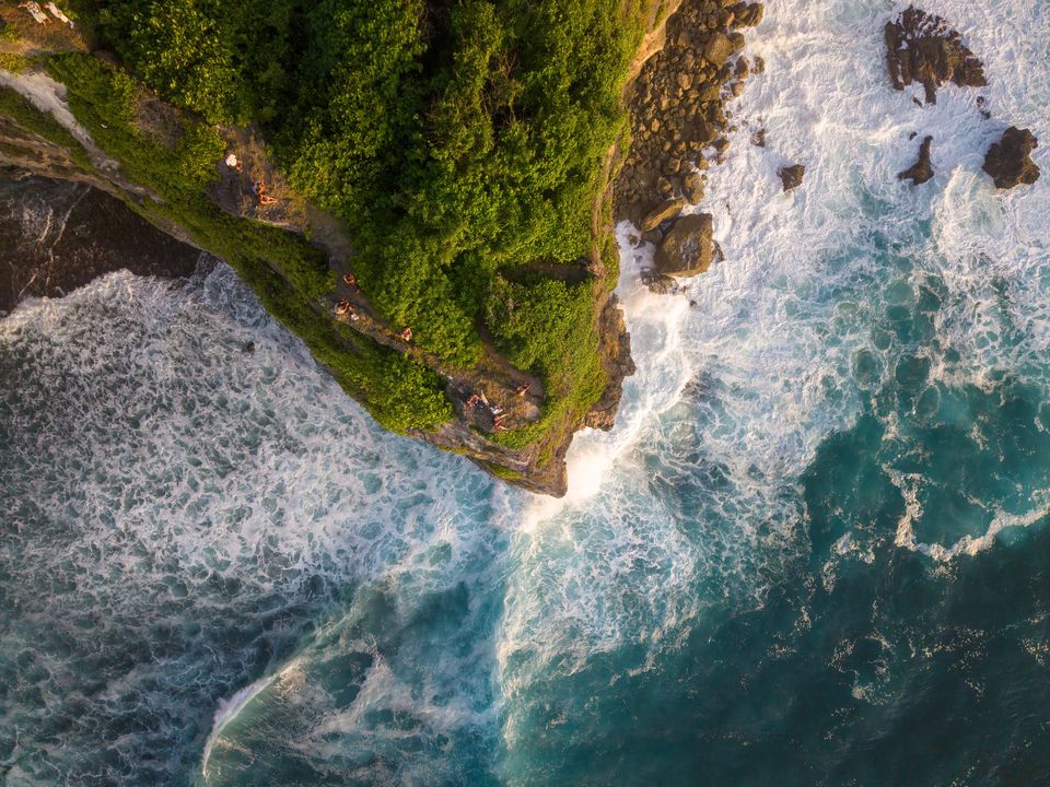 Ocean waves around a green coastal cliff in Bali